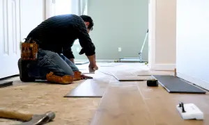 Fachowiec układa lvt panele na podłodze. Widać narzędzia i materiały.