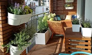 Jak urządzić mały wąski balkon w bloku inspiracje: zielone ściany, wygodne siedzisko i rattanowy fotel tworzą przytulną oazę.
