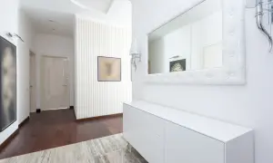 Nowoczesne lamele w przedpokoju dodają elegancji. Aranżacje z dużym lustrem i białą komodą tworzą przestronne wnętrze.