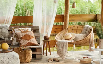 Relaks na tarasie w stylu boho. Inspiracje z wiklinowym fotelem, plecionym koszem i lnianymi poduszkami.