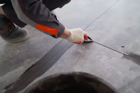 Pracownik nakłada fugę na taras zewnętrzny, dbając o estetykę i trwałość nawierzchni.
