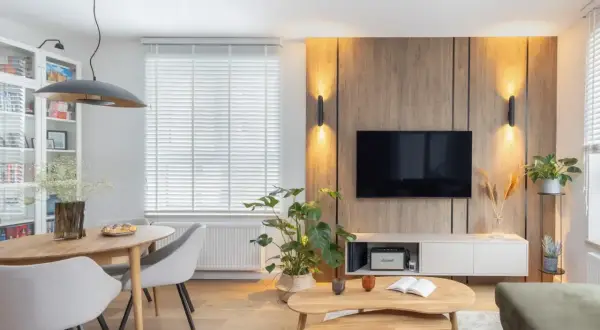 Przytulny salon inspiracje: drewniana ściana z TV, jadalnia, rośliny i wygodna sofa tworzą ciepłą atmosferę.