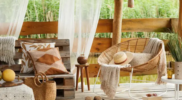Relaks na tarasie w stylu boho. Inspiracje z wiklinowym fotelem, plecionym koszem i lnianymi poduszkami.