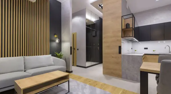 Nowoczesny salon z sofą i stolikiem kawowym. Ściana za sofą ozdobiona jest pionowymi lamelami, które nadają wnętrzu ciepła i elegancji.