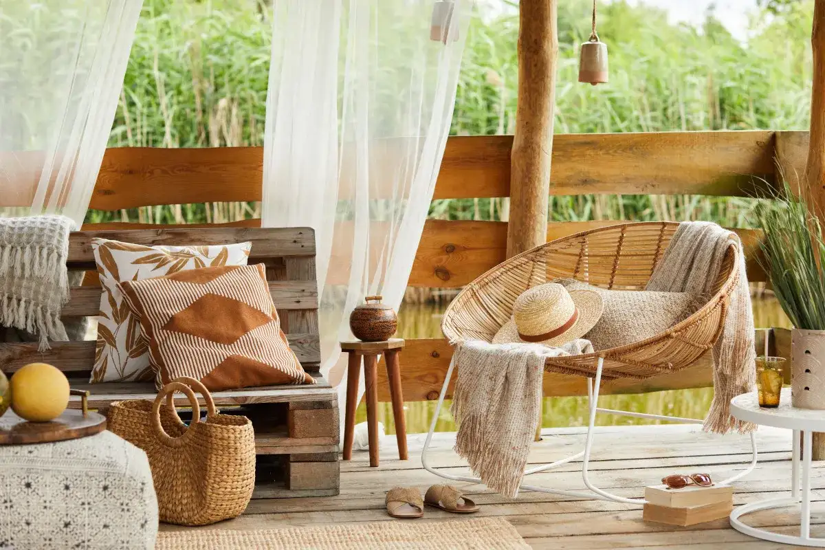 Relaks na tarasie w stylu boho. Inspiracje z wiklinowym fotelem, plecionym koszem i lnianymi poduszkami.
