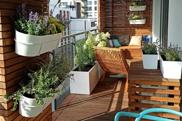 Jak urządzić mały wąski balkon w bloku inspiracje: zielone ściany, wygodne siedzisko i rattanowy fotel tworzą przytulną oazę.