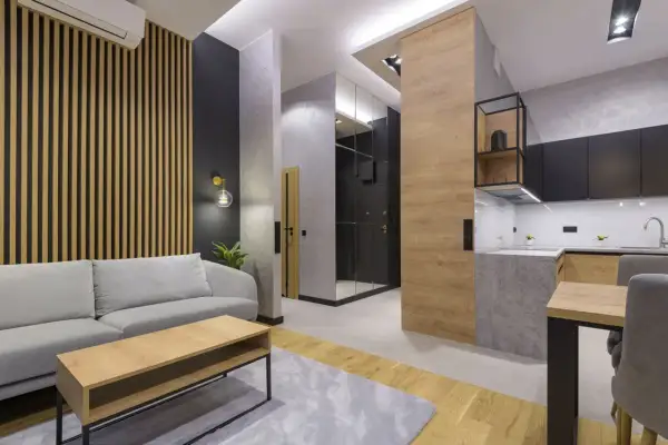 Nowoczesny salon z sofą i stolikiem kawowym. Ściana za sofą ozdobiona jest pionowymi lamelami, które nadają wnętrzu ciepła i elegancji.